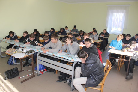 One of the fixed-up rooms. Notice insufficiant number of desks (some of them have bords instead of desk tops) and many boys being in their coats.