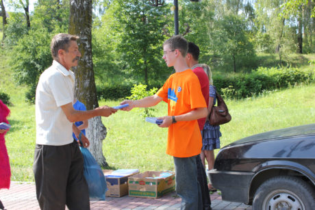 Sashko handing a New Testament to a visitor